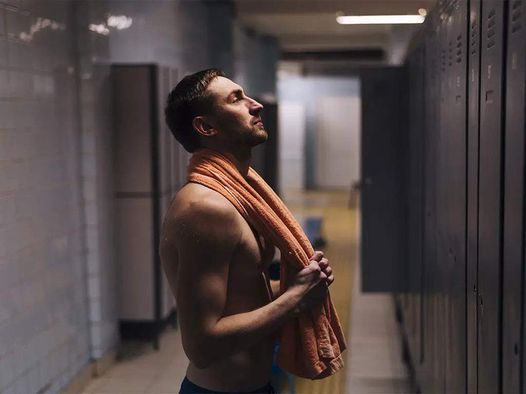 Athlete standing in a locker room after exercise with a towel