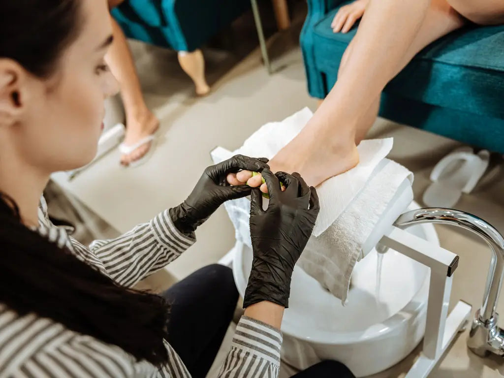 Nail technician performing a pedicure as part of a professional nail salon service